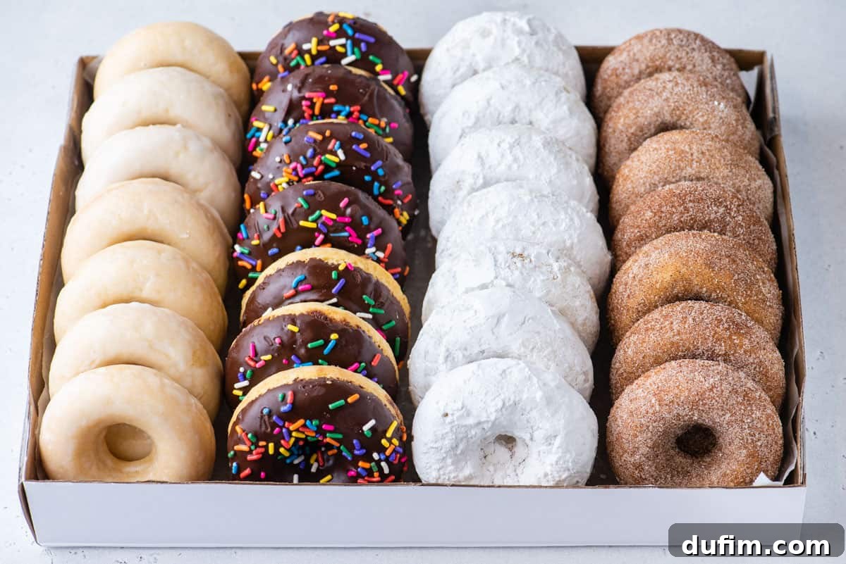 Effortless Donut Glaze Perfection 5 A box filled with an assortment of homemade donuts, including classic glazed, chocolate sprinkle, powdered sugar, and cinnamon sugar varieties.