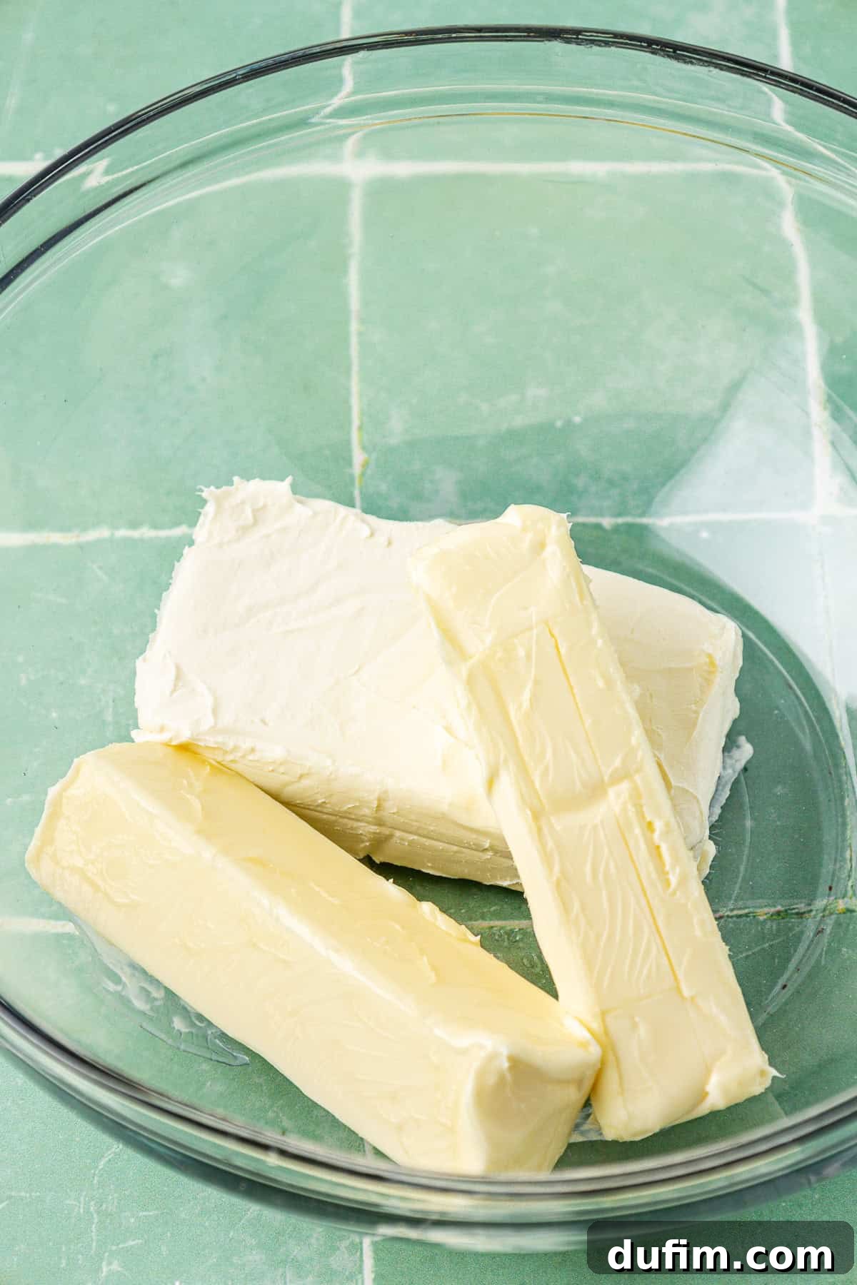 Luscious Lemon Cream Cheese Frosting 6 Two sticks of unsalted butter and a block of cream cheese in a clear glass mixing bowl, both at room temperature, ready for mixing.