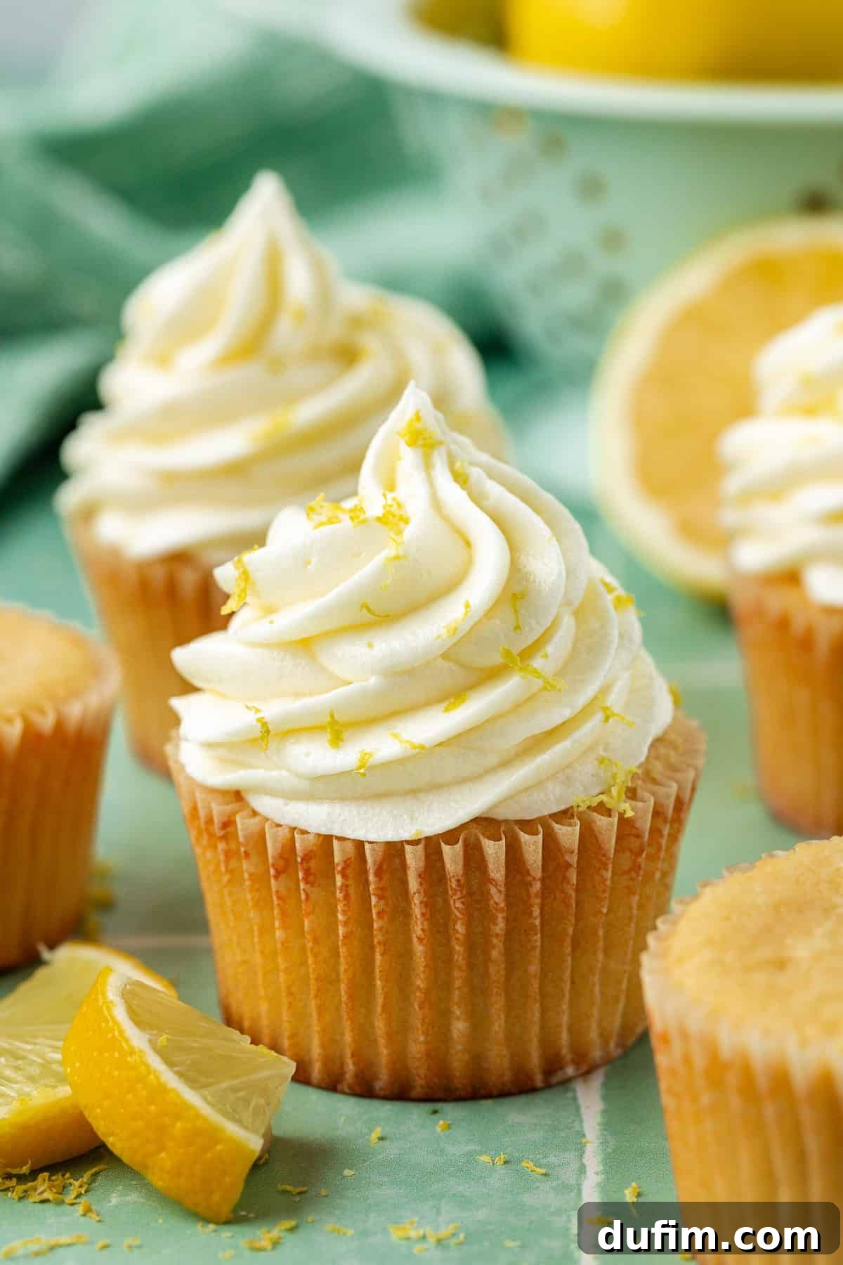 Luscious Lemon Cream Cheese Frosting 10 Delicious cupcakes topped with fluffy lemon cream cheese frosting and sprinkled generously with lemon zest, surrounded by more zest and fresh lemon slices for a vibrant presentation.