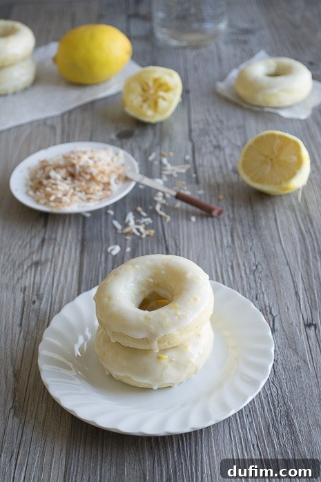 A plate of freshly baked Lemon Coconut Donuts with a light lemon drizzle