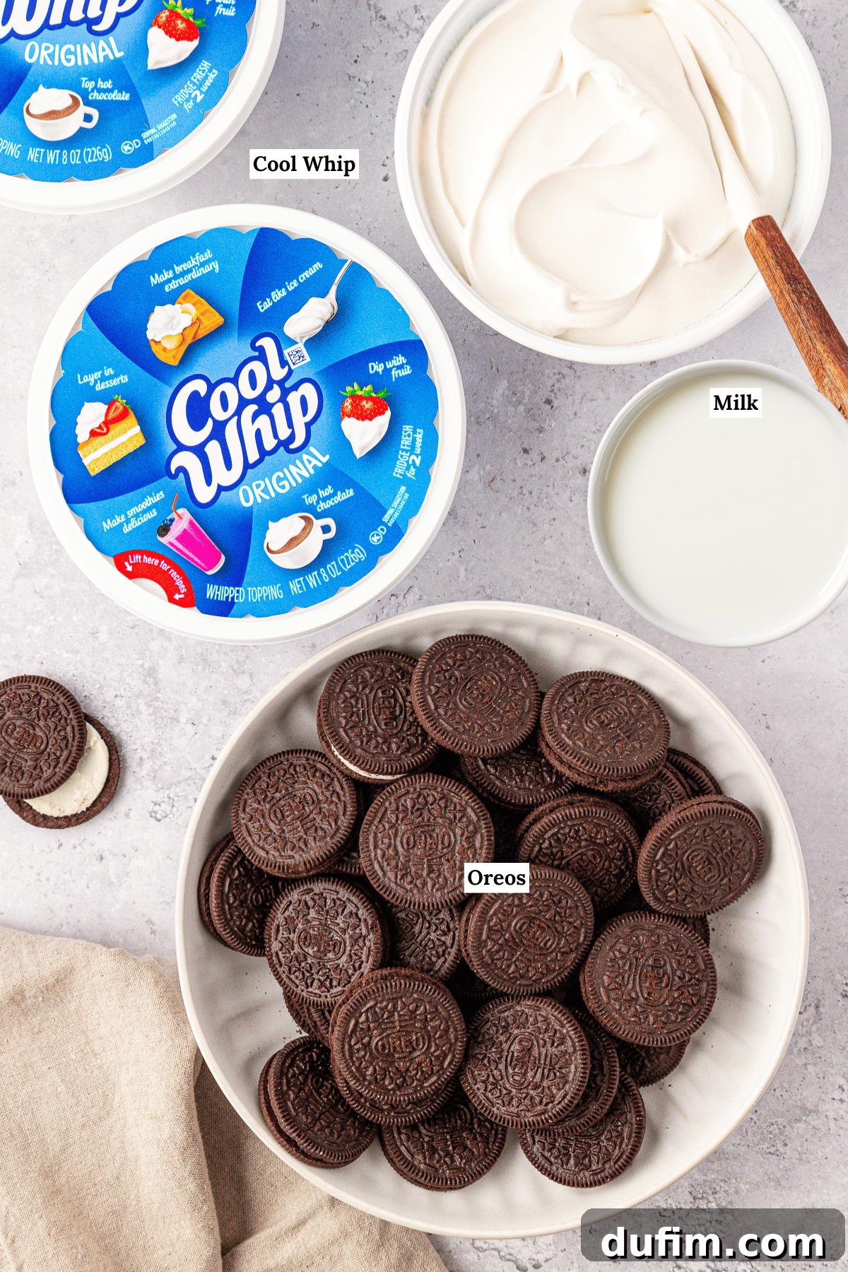 A bowl of whole Oreos, a bowl of Cool Whip whipped topping, and a bowl of milk sit on a countertop. Each item is labeled with text: Cool Whip, Milk, and Oreos.