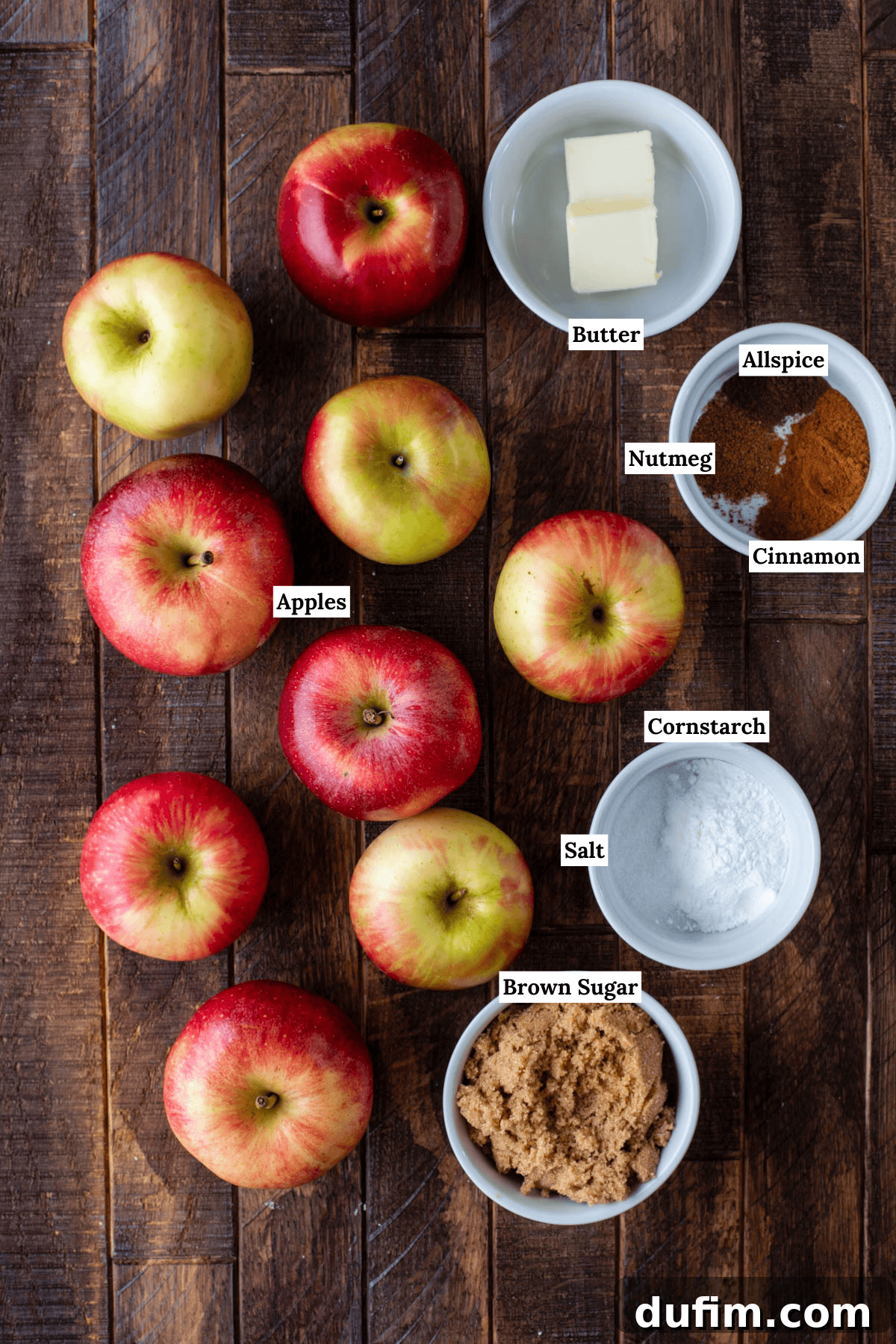 Warm Spiced Baked Apples 4 Apples and a few bowls of ingredients on a wood surface.
