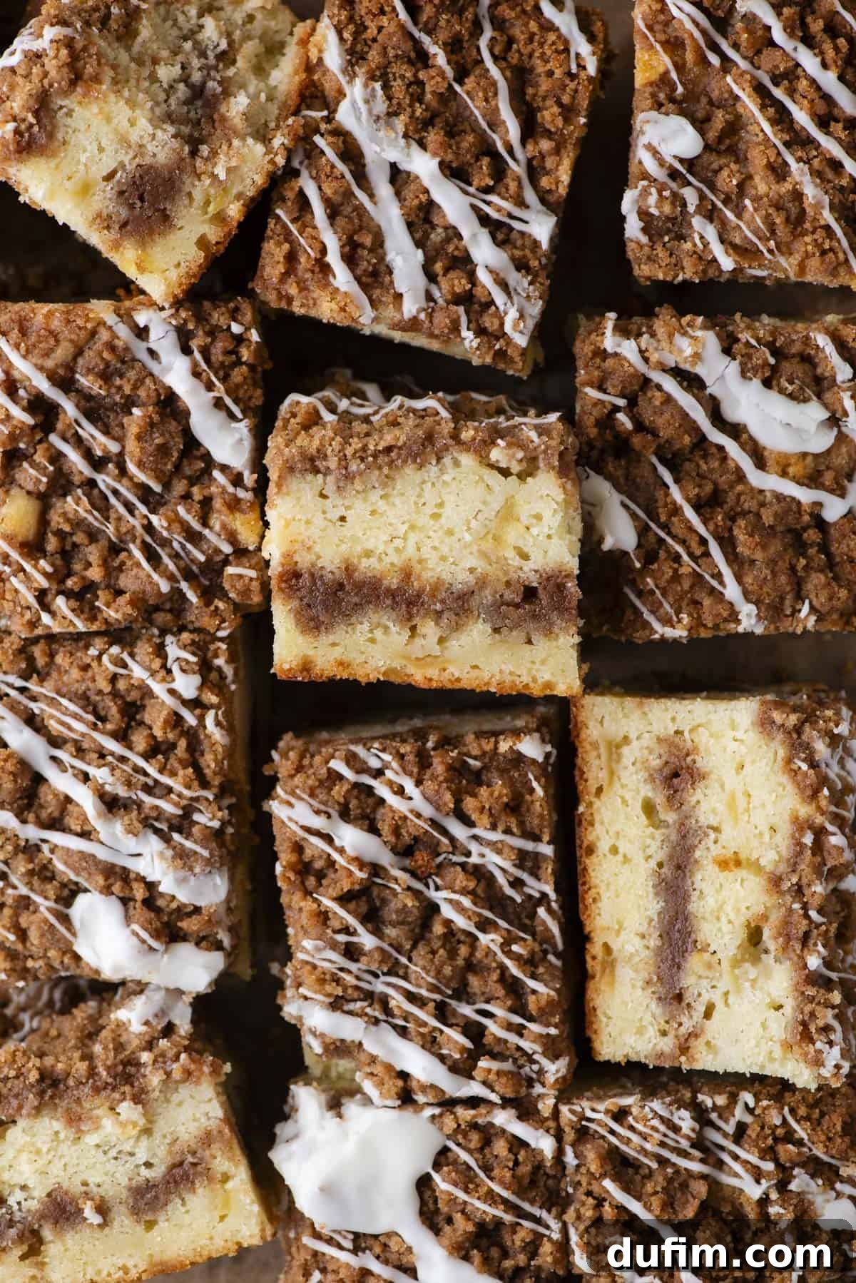Apple Cinnamon Streusel Coffee Cake 9 Close-up of several pieces of coffee cake with a crumbly cinnamon streusel topping and white icing drizzle, arranged closely together on a flat surface.