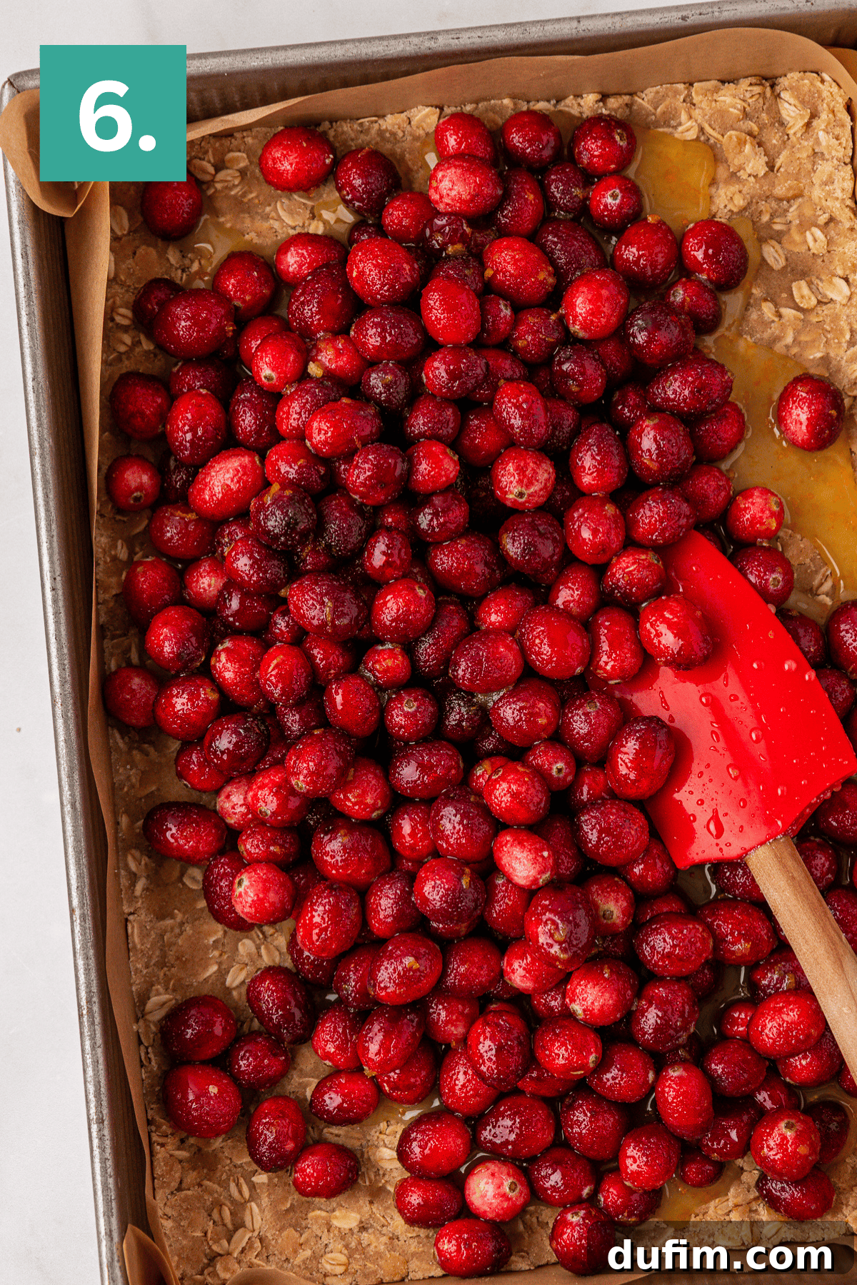 Overhead view of a 9x13 pan with a oat and crumb crust pressed into the bottom and sugar coated cranberries on top