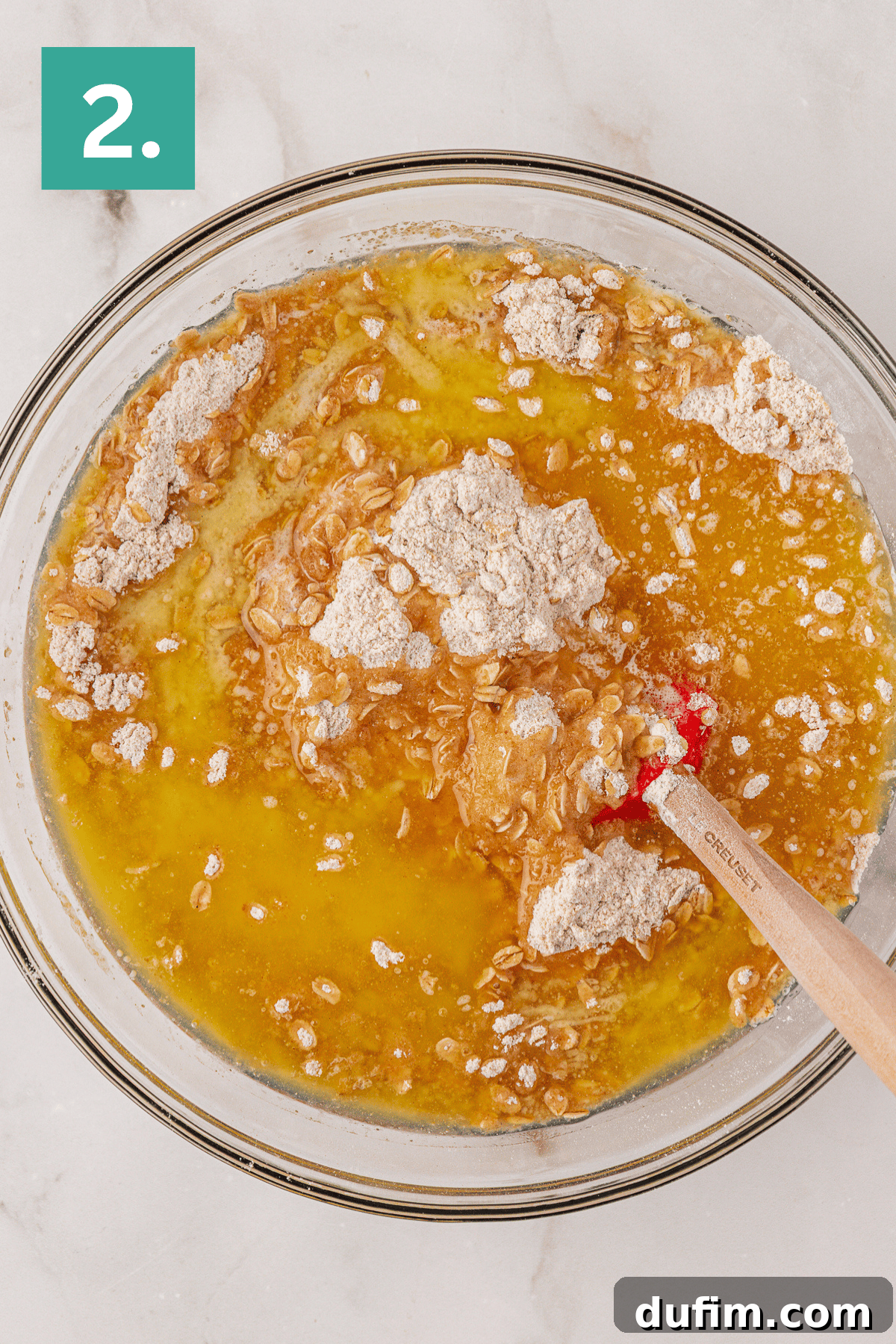 Melted butter on top of a oat and flour mixture in a large glass bowl