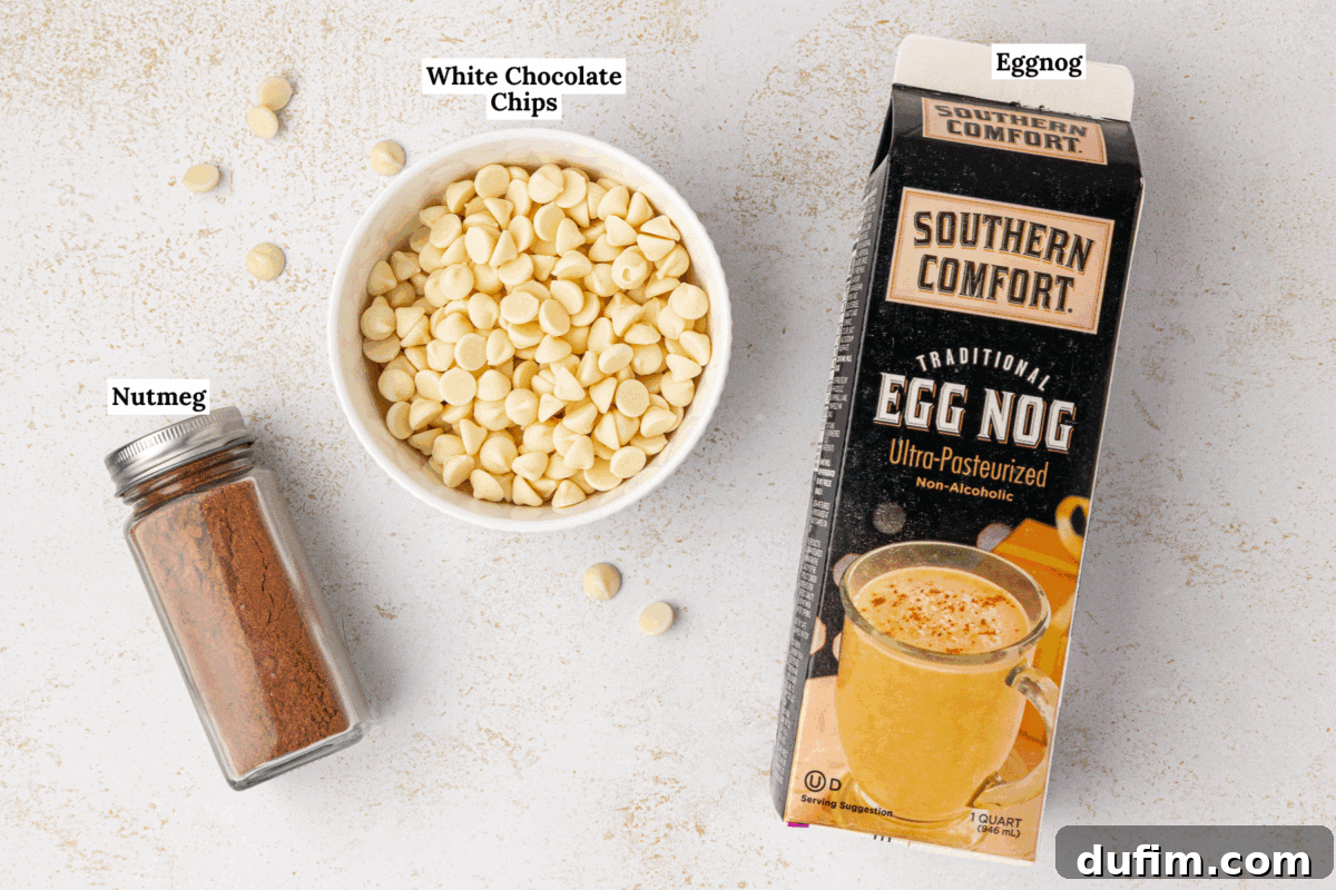 A carton of Southern Comfort eggnog, a glass jar of ground nutmeg, and a bowl of white chocolate chips are arranged on a light surface, with each ingredient labeled.