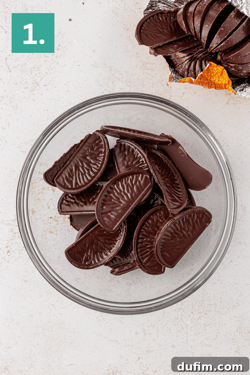 A glass bowl filled with chocolate orange segments sits on a light surface; more chocolate segments, partially wrapped in foil, are shown in the top right corner. A green box with the number 1 appears in the top left.
