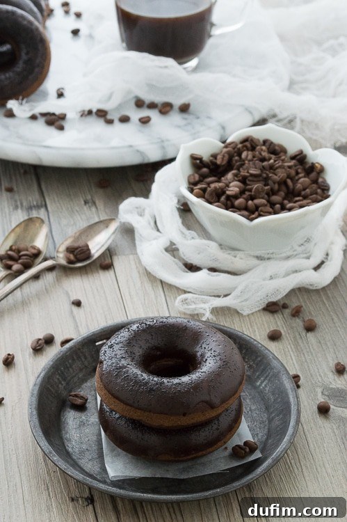 Brewed and Baked Bliss 2 Freshly baked coffee donuts with a luscious chocolate glaze, beautifully arranged next to a steaming cup of coffee and scattered coffee beans. The ideal combination for a delightful breakfast.