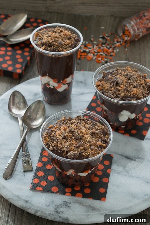 Halloween pudding parfait with brownies, marshmallows, chocolate pudding, and assorted mini Halloween candies.