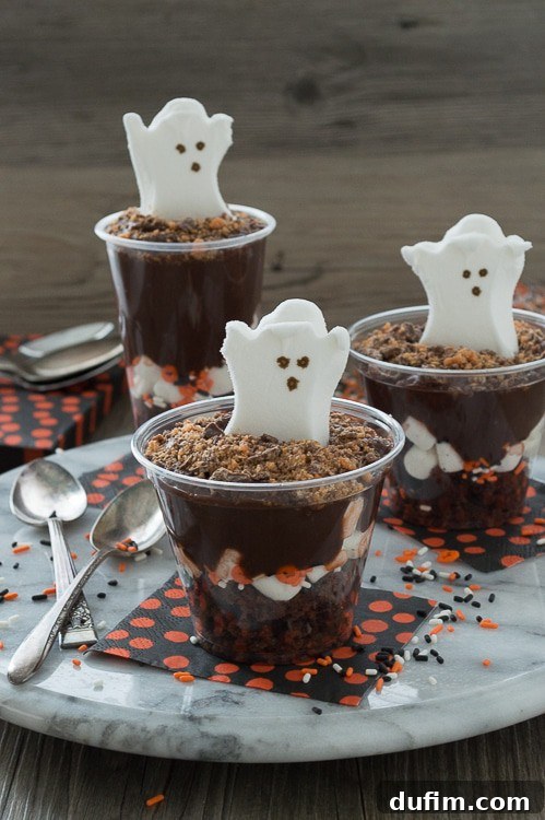 Close-up of a Halloween pudding parfait glass, showing layers of brownie, pudding, marshmallows, and candy.