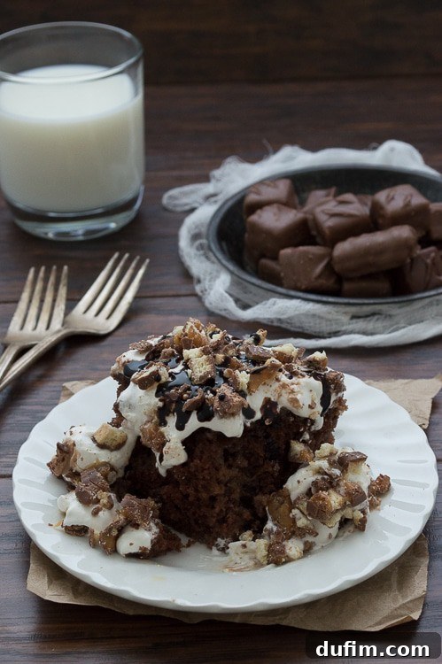 A close-up of the Candy Bar Cake being drizzled with rich chocolate sauce, highlighting the glossy finish and enticing texture of the cake.