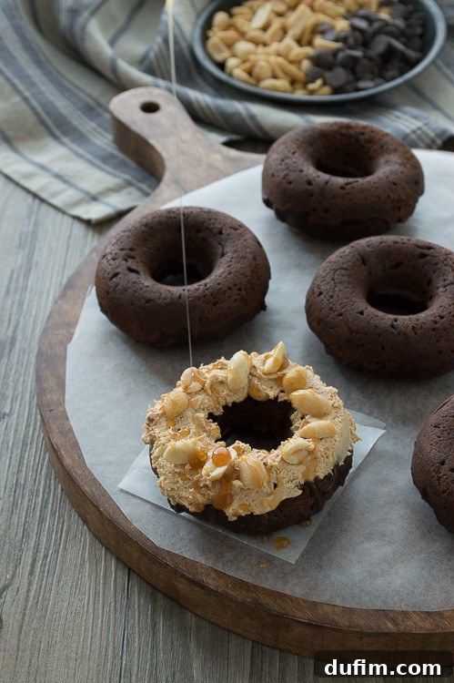 A single Snickers Donut artfully placed on a plate, highlighting its vibrant toppings and inviting texture.