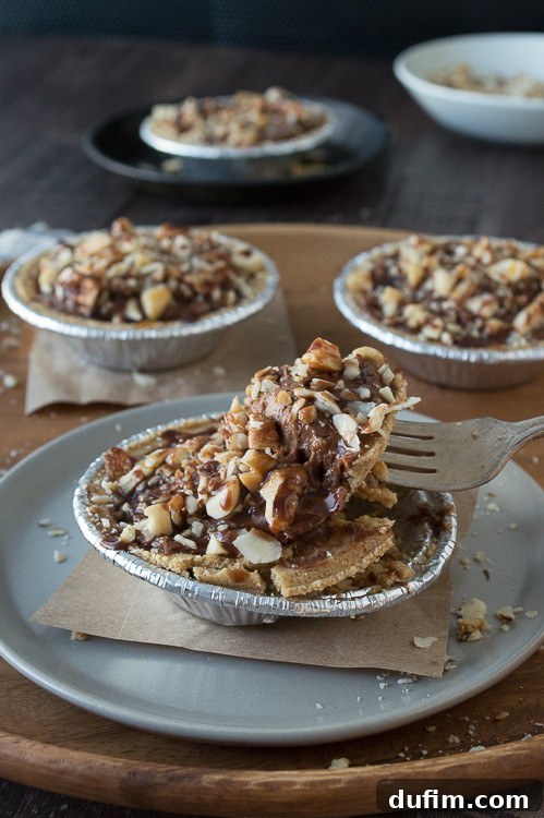 A captivating side view of a mini no-bake turtle pie, meticulously showcasing the distinct, mouth-watering layers of nuts and creamy chocolate filling.