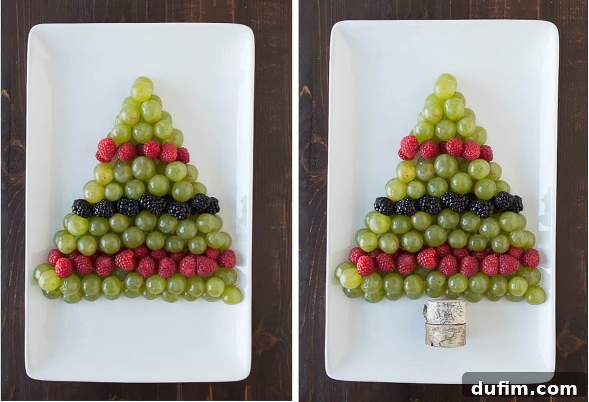 A wide shot of the green grapes, raspberries, and blackberries artfully arranged to form a Christmas tree shape on a pristine white platter, highlighting the festive design.