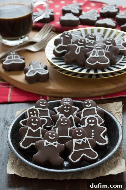 Close-up of a gingerbread man Oreo ball, showing its smooth chocolate coating and intricate white icing decoration, ready for a holiday gathering.
