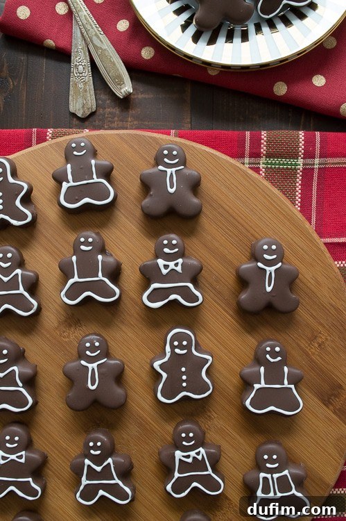 Several gingerbread man Oreo balls displayed, showcasing various hand-drawn icing designs, perfect for a personalized Christmas treat.