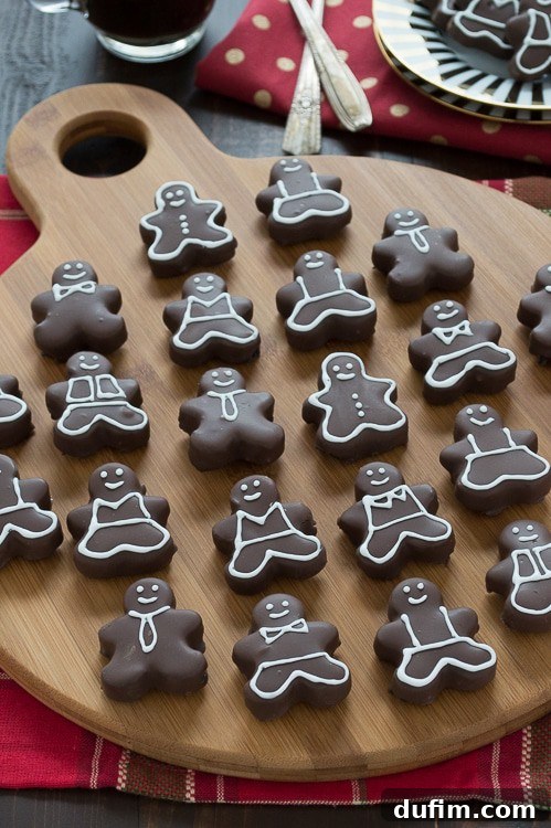 A close-up of a perfectly dipped and decorated gingerbread man Oreo ball, showcasing the rich chocolate and delicate icing work against a festive backdrop.