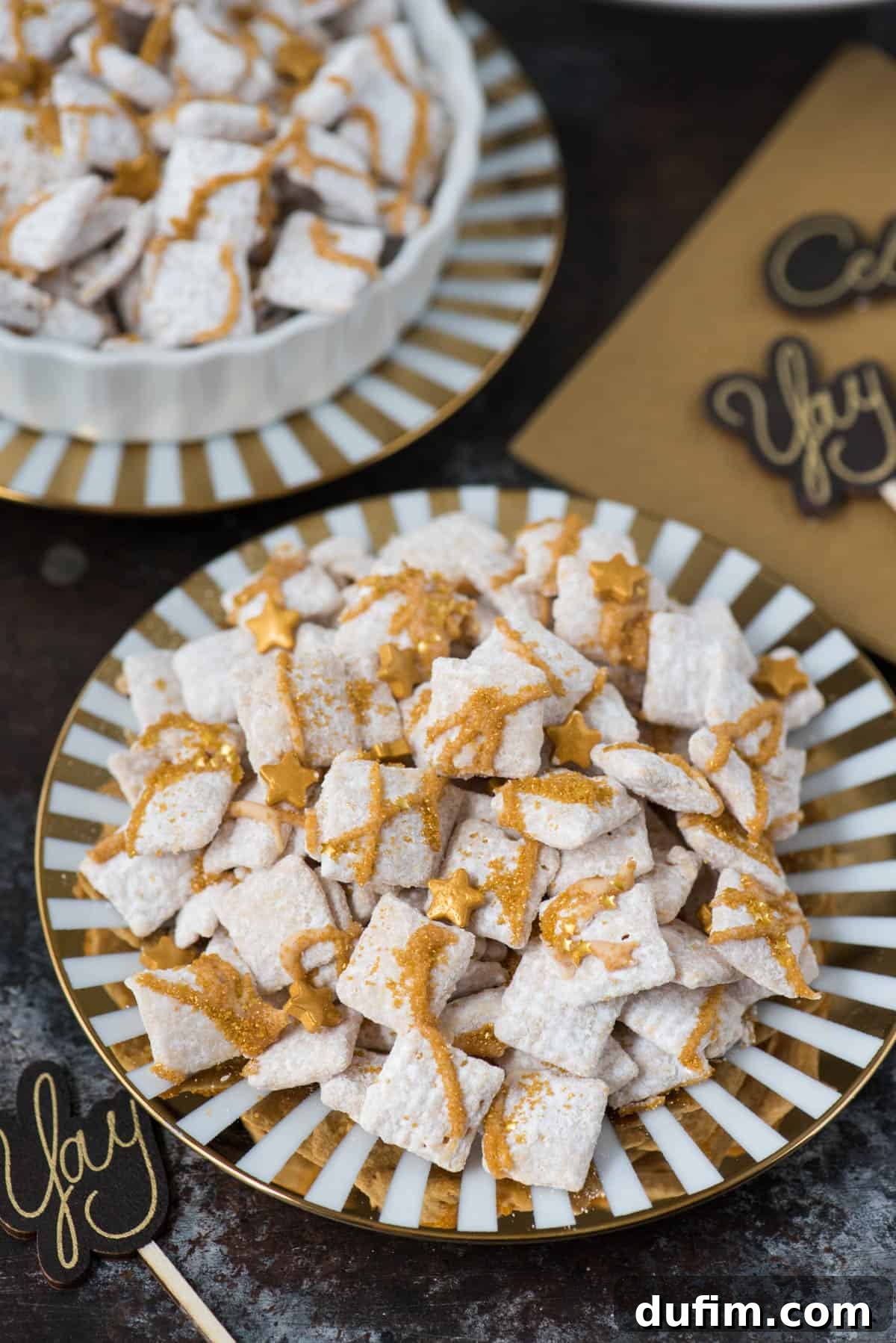 Sparkling White Chocolate New Year's Chow 2 New Year's Eve white chocolate puppy chow with gold sprinkles and gold stars on a gold striped plate against a dark background, radiating festive elegance.