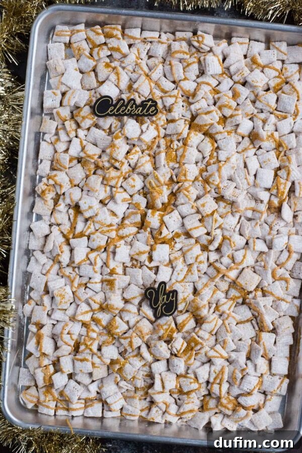Sparkling White Chocolate New Year's Chow 5 New Year's Eve white chocolate puppy chow with gold sprinkles and gold stars spread on a baking sheet, allowing it to set before serving.