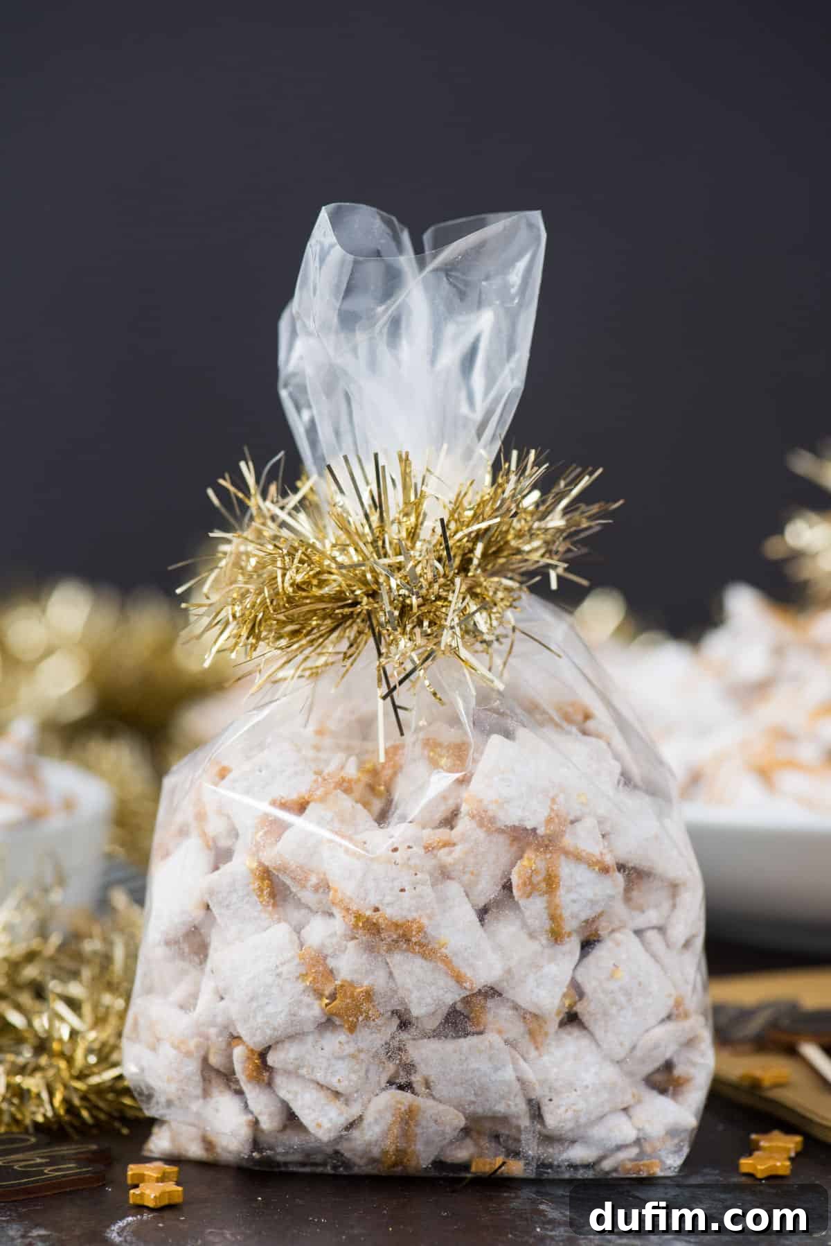 Sparkling White Chocolate New Year's Chow 7 Individual serving of New Year's Eve white chocolate puppy chow, neatly packaged in a cellophane bag and tied with a festive gold ribbon, perfect for gifting as a party favor.
