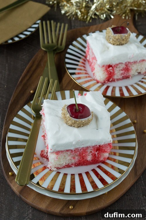 Close-up of the Champagne Cherry Poke Cake with whipped cream topping and a beautiful white chocolate-dipped, gold glitter cherry garnish. The cake is moist and vibrant.