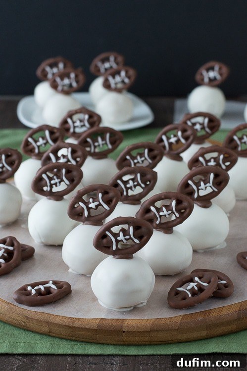 Football Oreo Balls - golden oreo balls dipped in white chocolate and topped with football pretzels! Make these for game day!