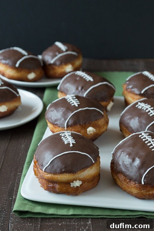 Pigskin Perfection Donuts 5 A hand gently dipping a football-shaped donut into melted chocolate glaze