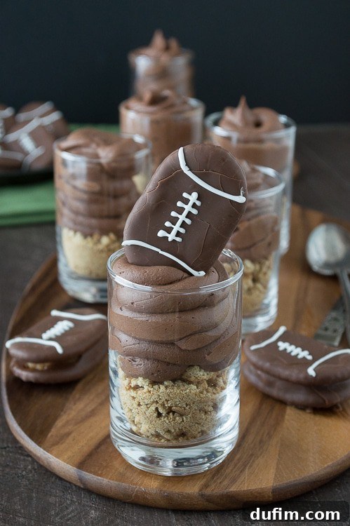 Chocolate cheesecake football dessert shooters topped with peanut butter stuffed chocolate footballs. A great recipe for game day!