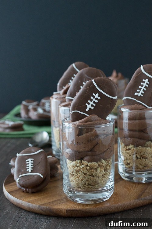 Chocolate cheesecake football dessert shooters topped with peanut butter stuffed chocolate footballs. A great recipe for game day!