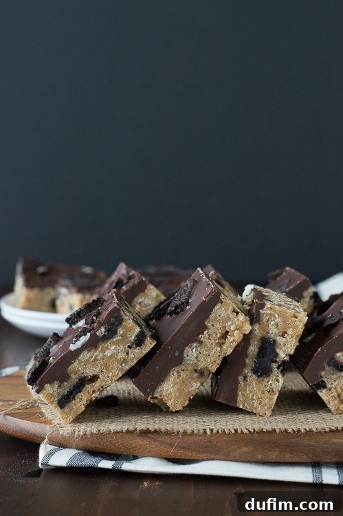 Decadent Oreo Scotcheroo Bars 3 Close-up of freshly cut Oreo Scotcheroos, showing the layers of cereal base and chocolate topping with visible Oreo crumbs.