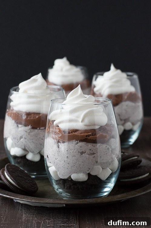 Close-up of a glass Over the Top Chocolate Cheesecake Oreo Parfait, showing distinct layers of creamy chocolate, white fluff, and cookie crumbs