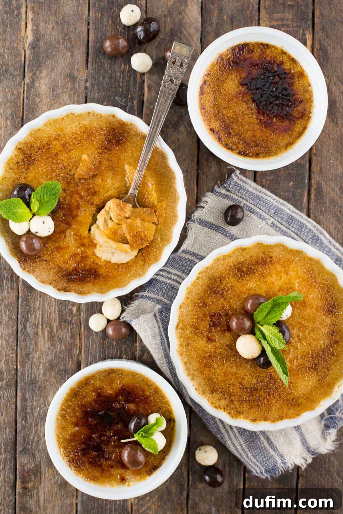 Close-up of a single serving of espresso crème brûlée in a clean white ramekin, elegantly topped with coffee beans coated in chocolate and a vibrant green mint leaf.