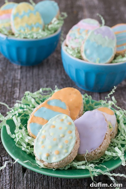 Five Rice Krispies Easter Eggs with colorful royal icing on a green serving plate on a wooden table, ready to be enjoyed.