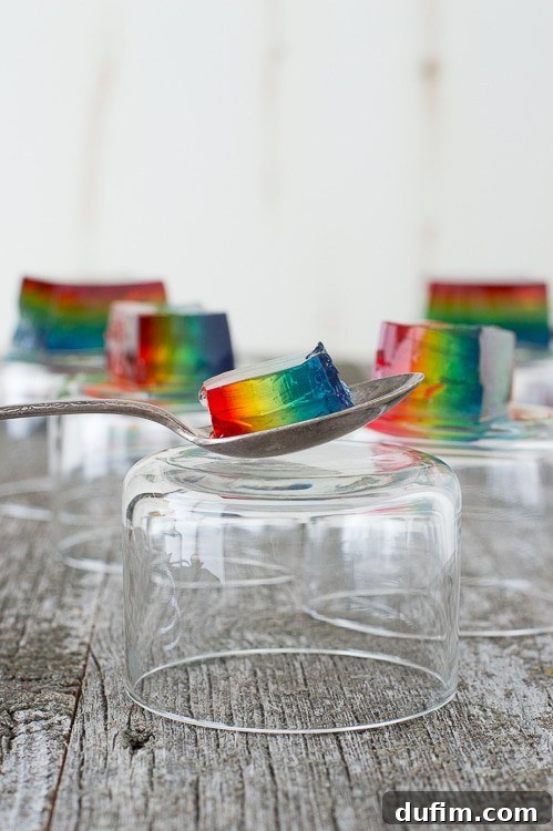Close-up of freshly cut Rainbow Jello squares, showing the distinct and vibrant layers of red, orange, yellow, green, blue, and purple jello.