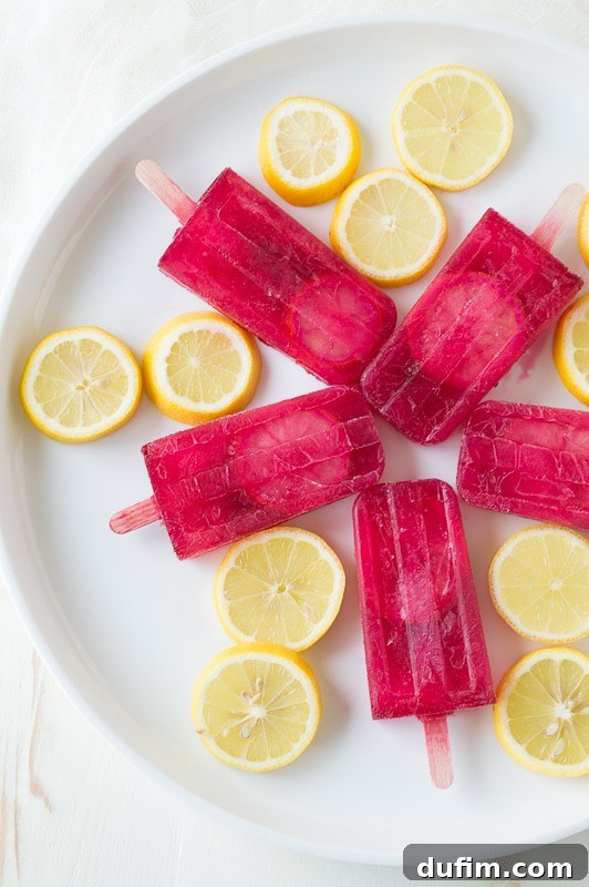 Passion Tea Lemonade Popsicles - everyone’s favorite Starbucks drink made into popsicles! Two popsicles side-by-side on a rustic surface.