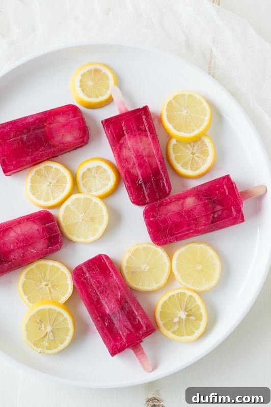 Passion Tea Lemonade Popsicles - everyone’s favorite Starbucks drink made into popsicles! A single popsicle is held up against a blurred outdoor background.
