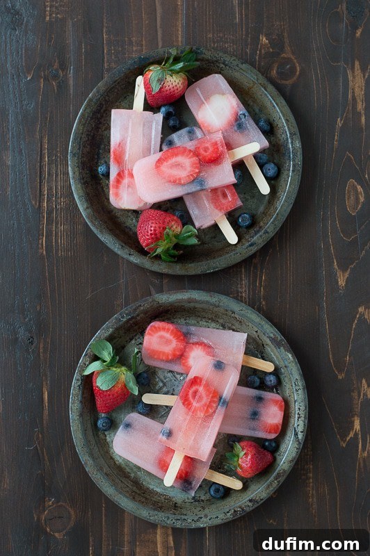 Zesty Berry Lemonade Pops 4 A large glass pitcher filled with vibrant pink berry lemonade, garnished with fresh berries.