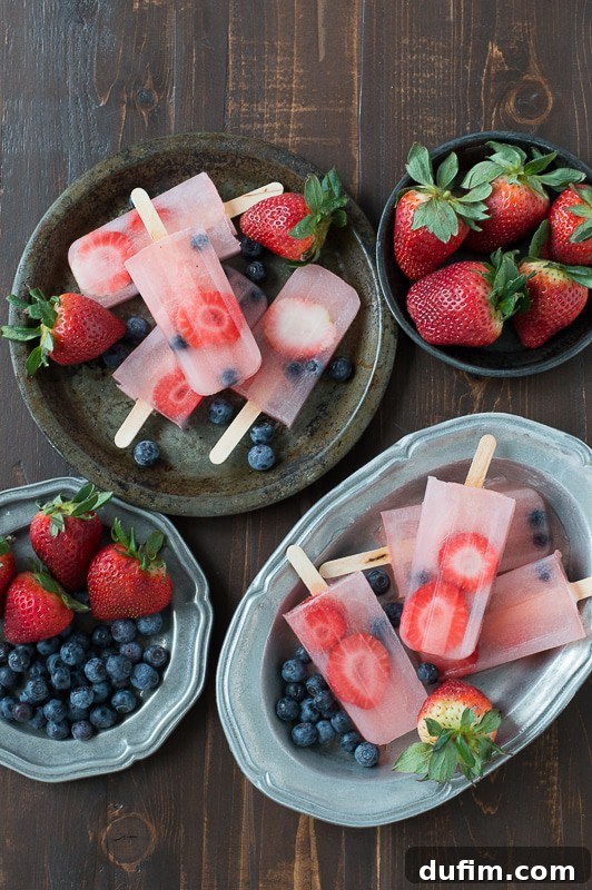 Zesty Berry Lemonade Pops 7 A hand holding a beautifully frozen Berry Lemonade Popsicle, showcasing the vibrant fruit pieces within.