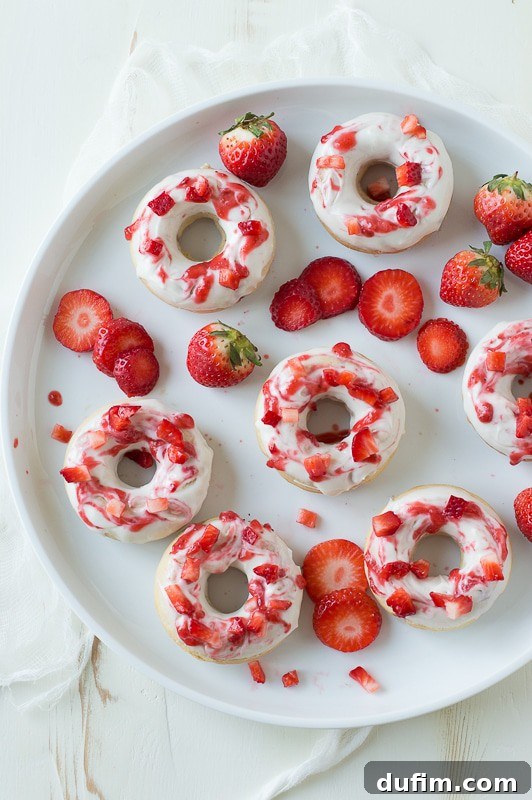 Strawberry Cheesecake Donut Delights 5 A close-up of a Strawberry Cheesecake Donut, showing a perfect cross-section with a fluffy interior, visible strawberry pieces, and a generous coating of glaze and coulis.