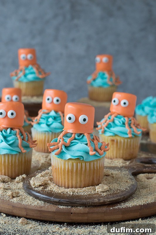 Seven orange and blue Octopus Cupcakes on a wooden board, ready for an under the sea party.