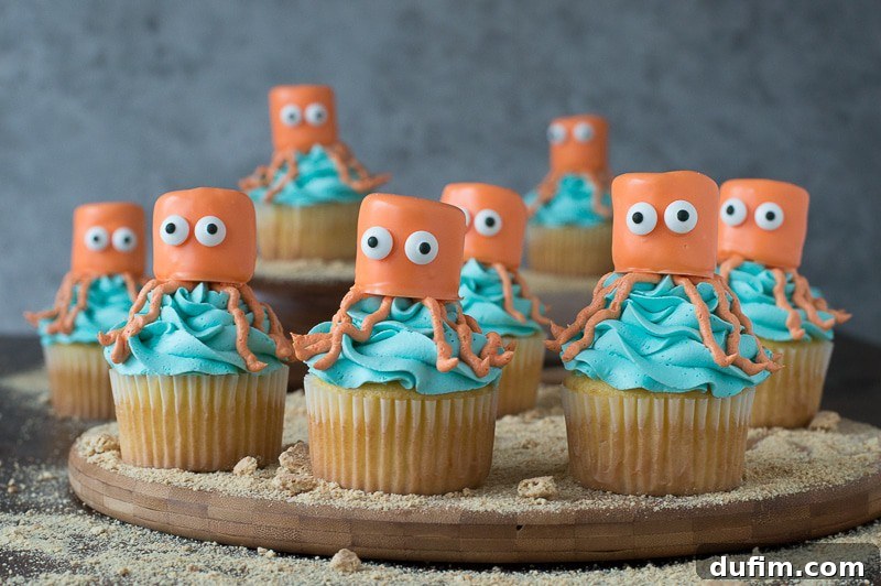 Eight delicious Octopus Cupcakes arranged on on a wooden board, showcasing their vibrant colors and cute googly eyes for the perfect under the sea party!