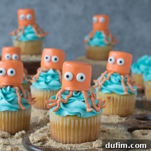A beautifully decorated Octopus Cupcake, topped with blue frosting and an orange marshmallow octopus, perfect for an under the sea party.