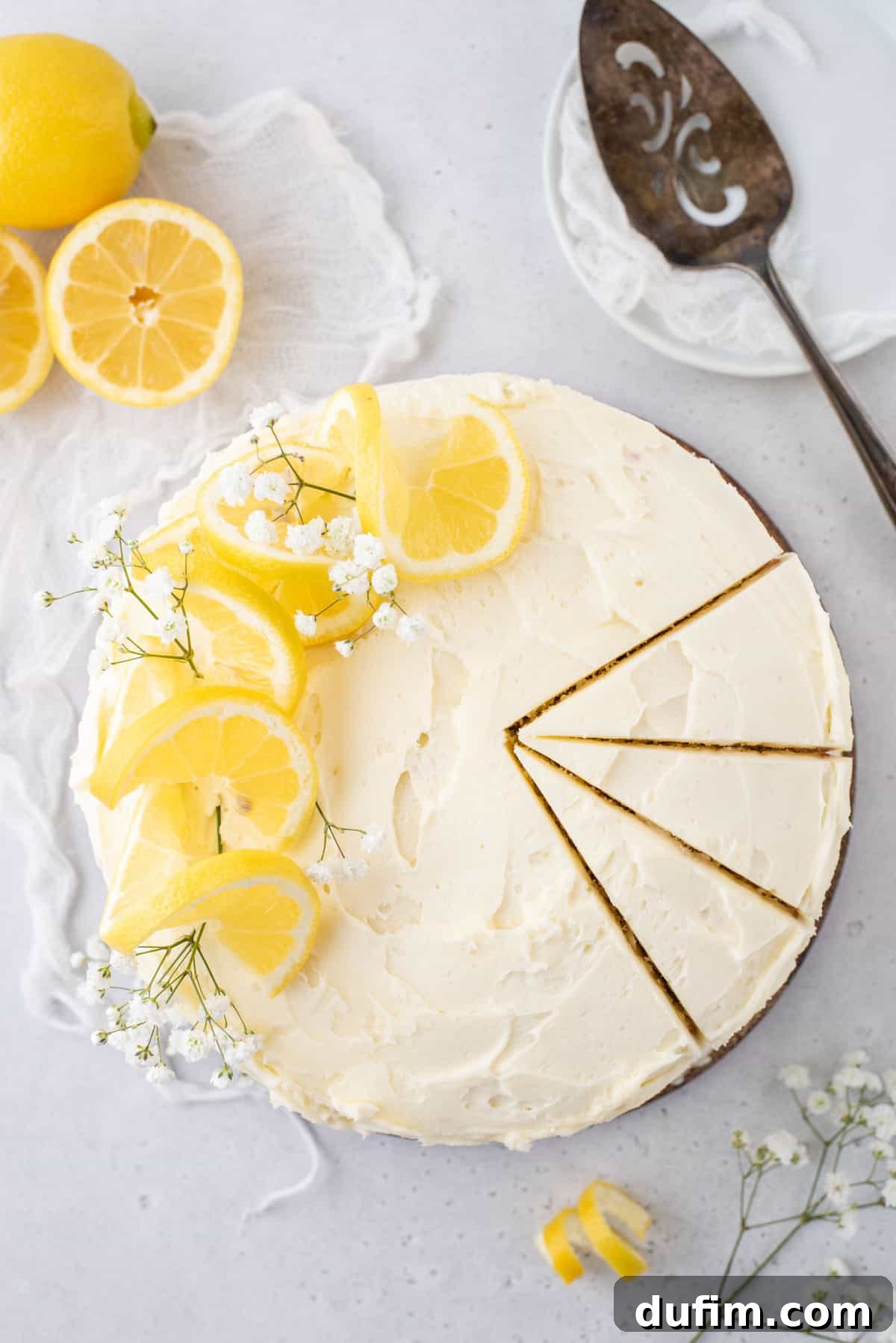 Overhead view of round lemon layer cake, with 3 slices cut, showcasing its moist texture and vibrant lemon frosting.