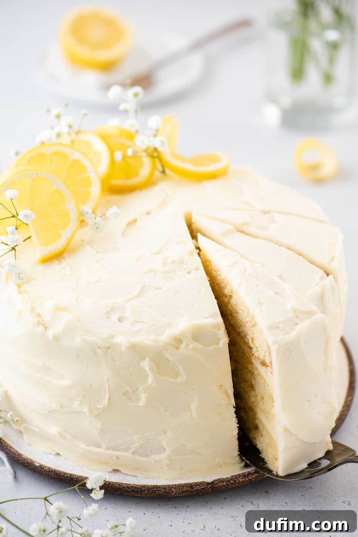 A hand gently pulling out a perfect slice of lemon layer cake from the main cake, revealing its beautiful layers.