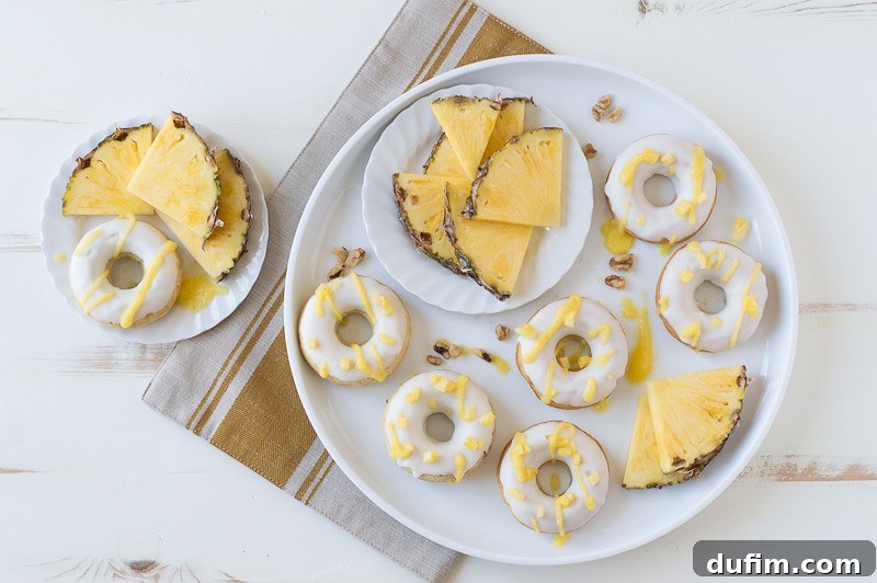 Several Pineapple Walnut Donuts arranged on a wire cooling rack, illustrating the final glazing and drizzling process.