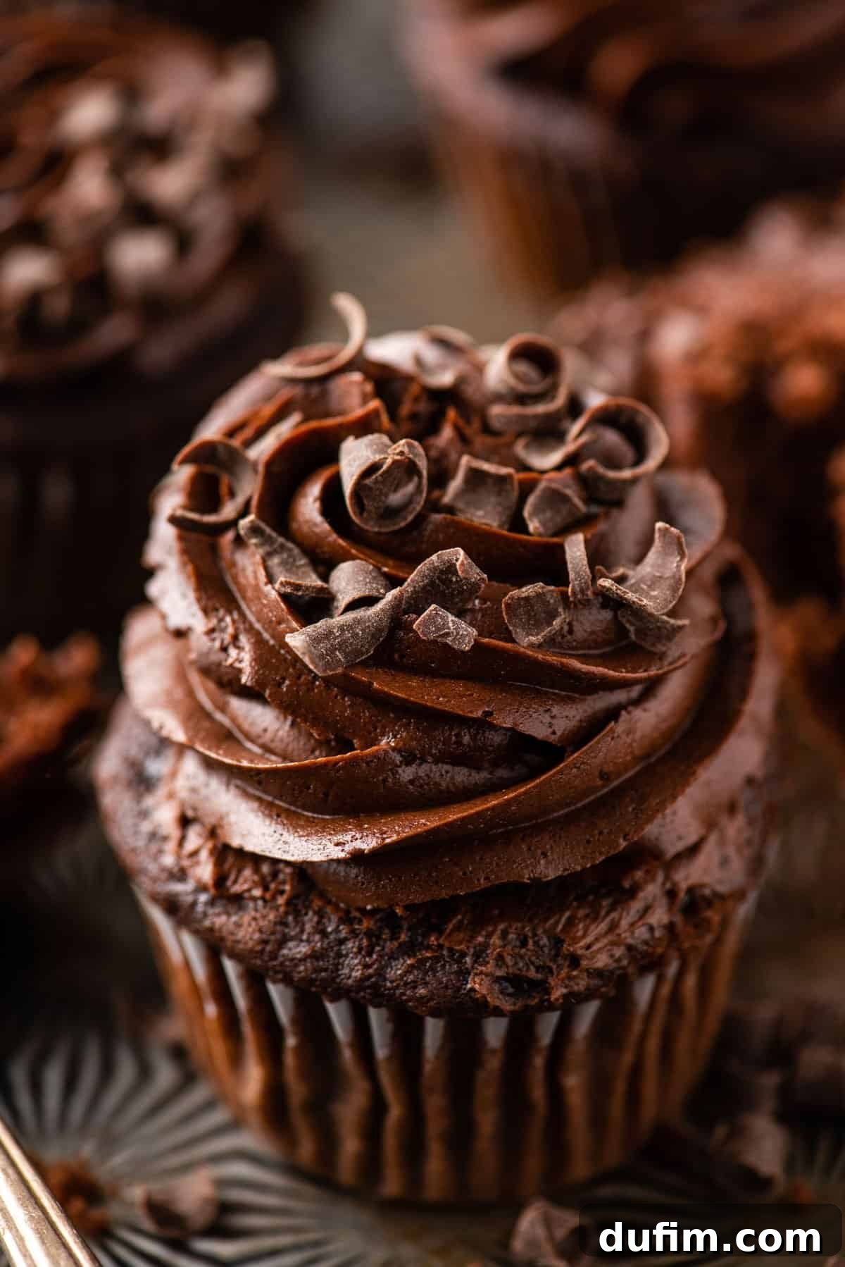 Decadent Chocolate Delights 7 chocolate cupcake with chocolate frosting on metal background with more cupcakes in the distance