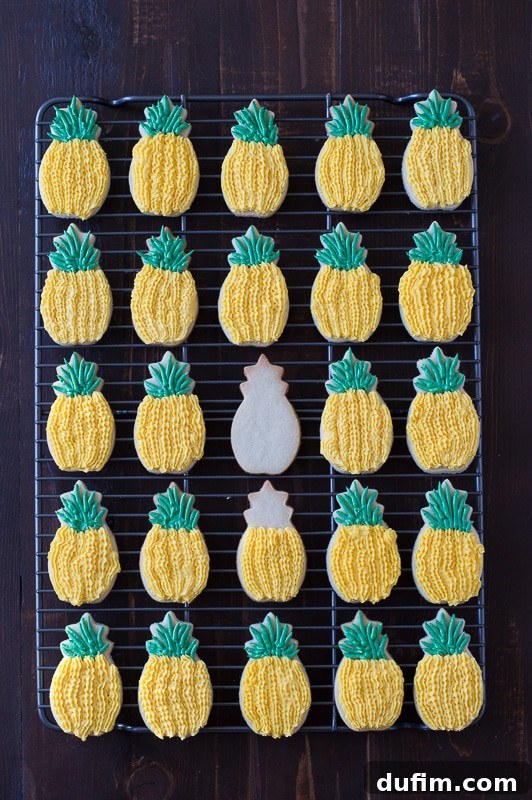 Close-up of Pineapple Sugar Cookies with pineapple extract. The cookies are shaped like pineapples and decorated with yellow and green buttercream frosting to resemble the fruit.