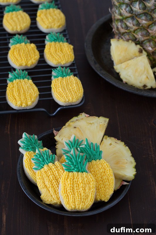Adorable Pineapple Sugar Cookies arranged on a plate, showcasing their intricate yellow and green buttercream frosting. These cookies are infused with pineapple extract.