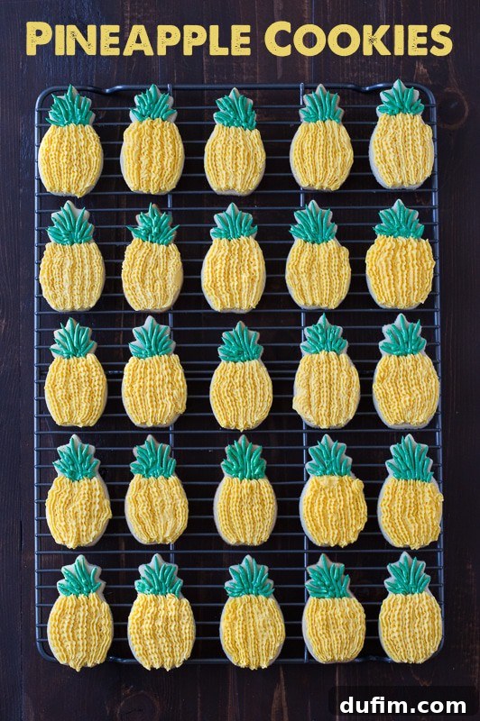 A stack of beautifully decorated Pineapple Sugar Cookies, featuring detailed yellow and green frosting. They are perfect for a luau or summer party.