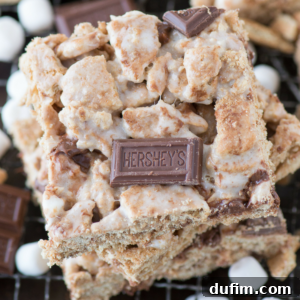 Close-up of gooey and crumbly smores bars made with graham crackers, mini marshmallows, and Hershey’s chocolate pieces, stacked to showcase the irresistible layers of chocolate and marshmallow.